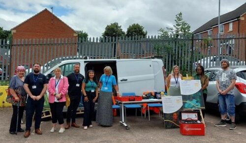 Customers and staff stand together at a repairs roadshow event